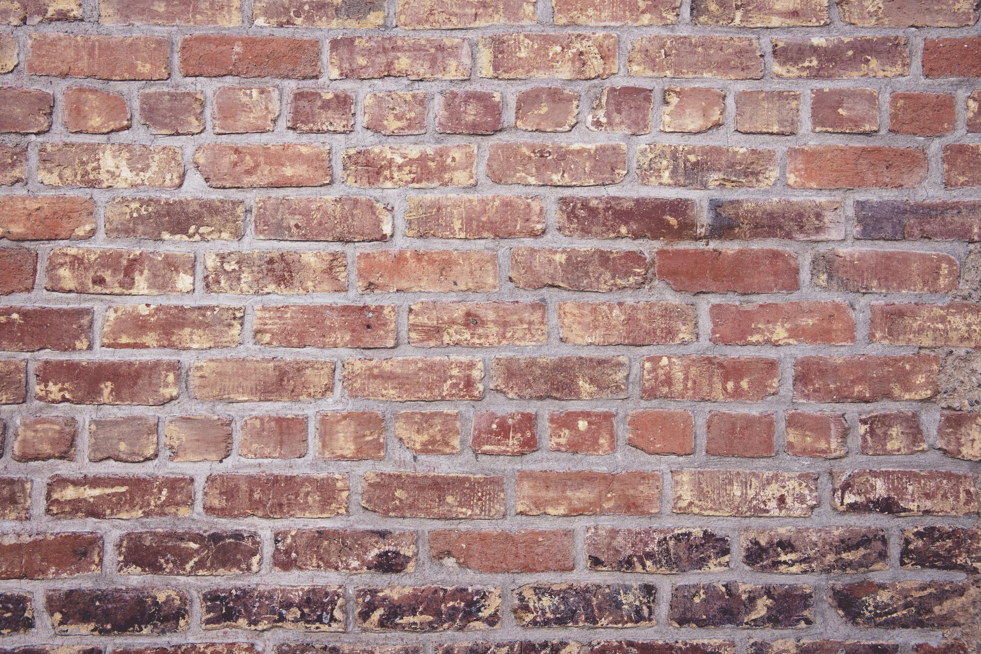 Red brick wall with varying shades of brown and gray mortar.