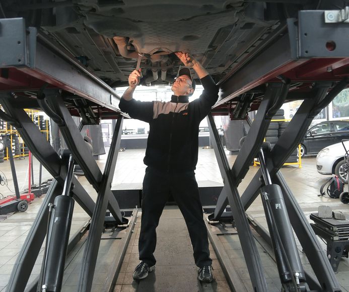A man is working underneath a car on a lift