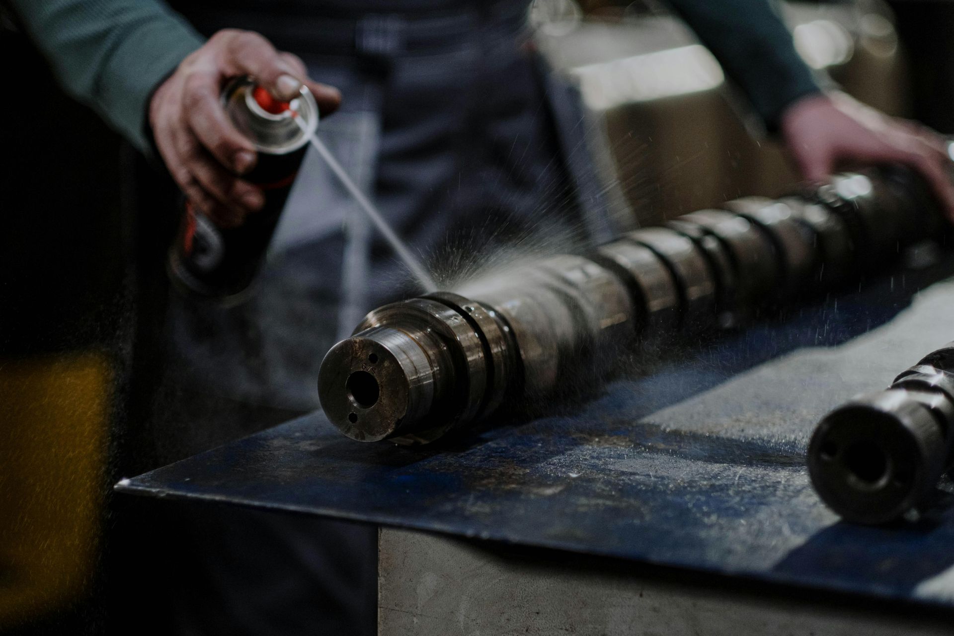 A man is spraying a can of lubricant on a metal object.