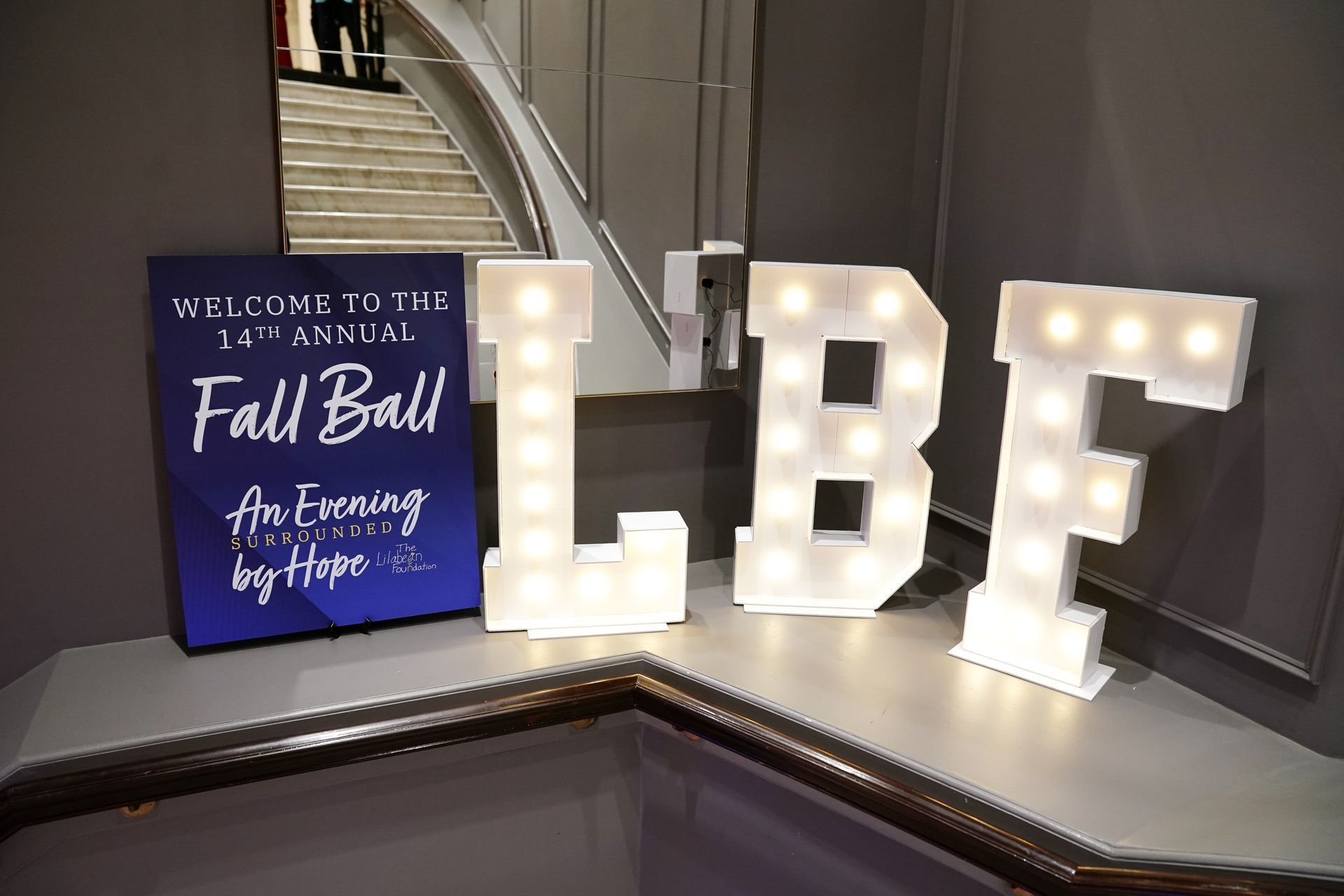 A blue sign for the 1st Annual LBF Fall Ball stands next to large, illuminated marquee letters reading