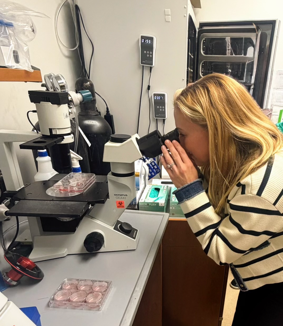 Stewie Corno looking through a microscope in the lab