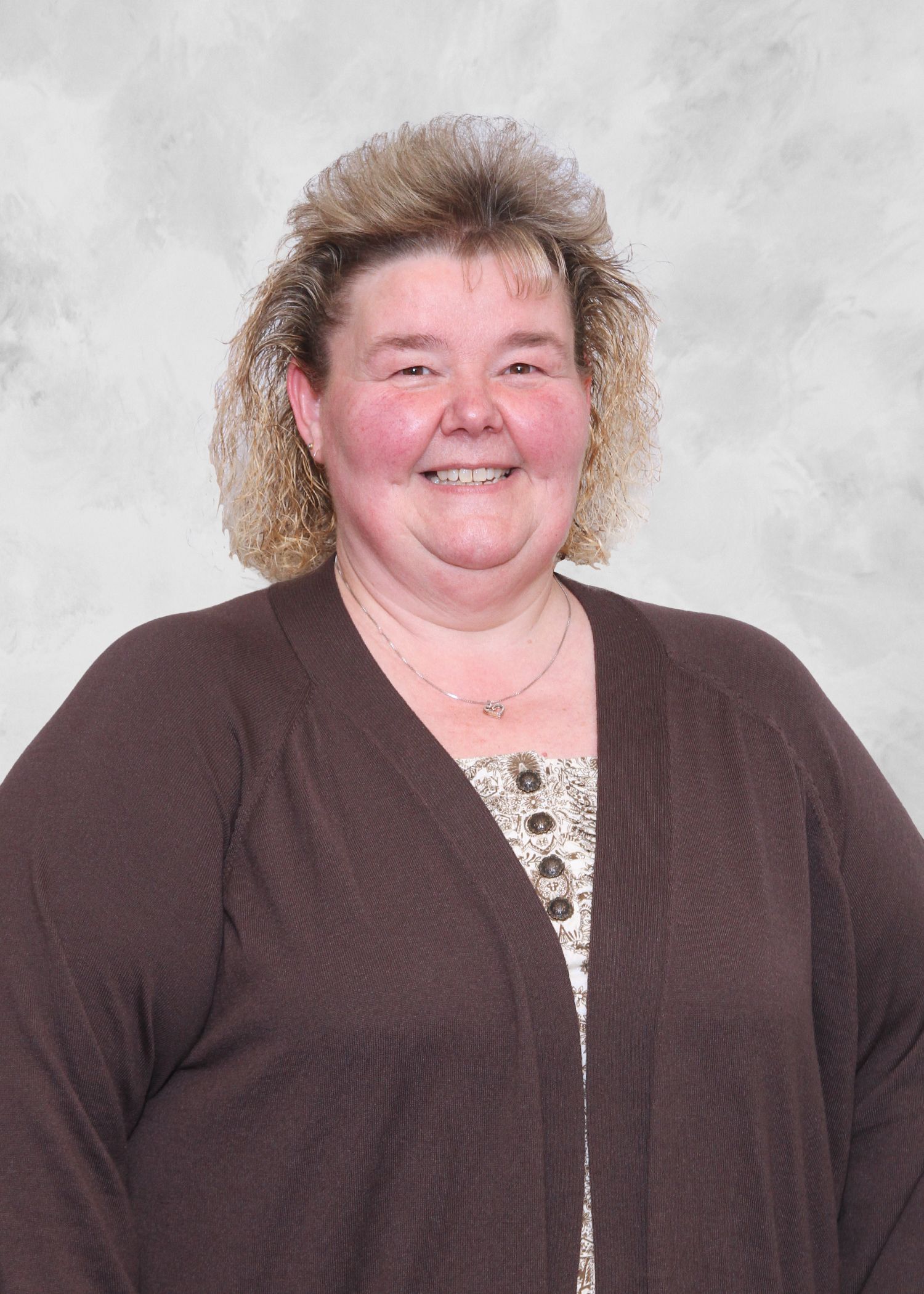 Woman with curly blonde hair and brown cardigan smiles.