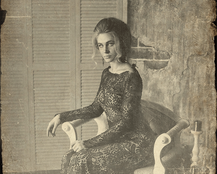 A woman in a black dress is sitting in a chair.