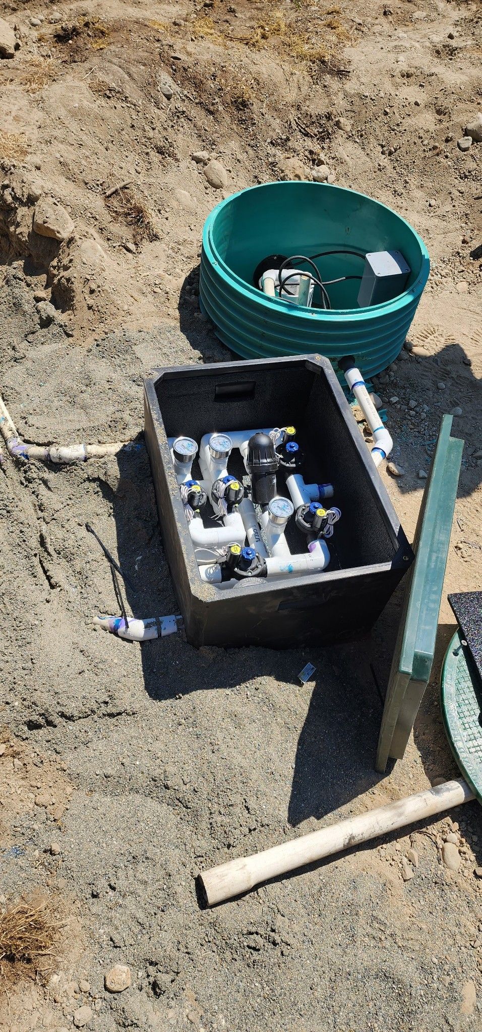 A box filled with pipes is sitting on top of a pile of dirt.