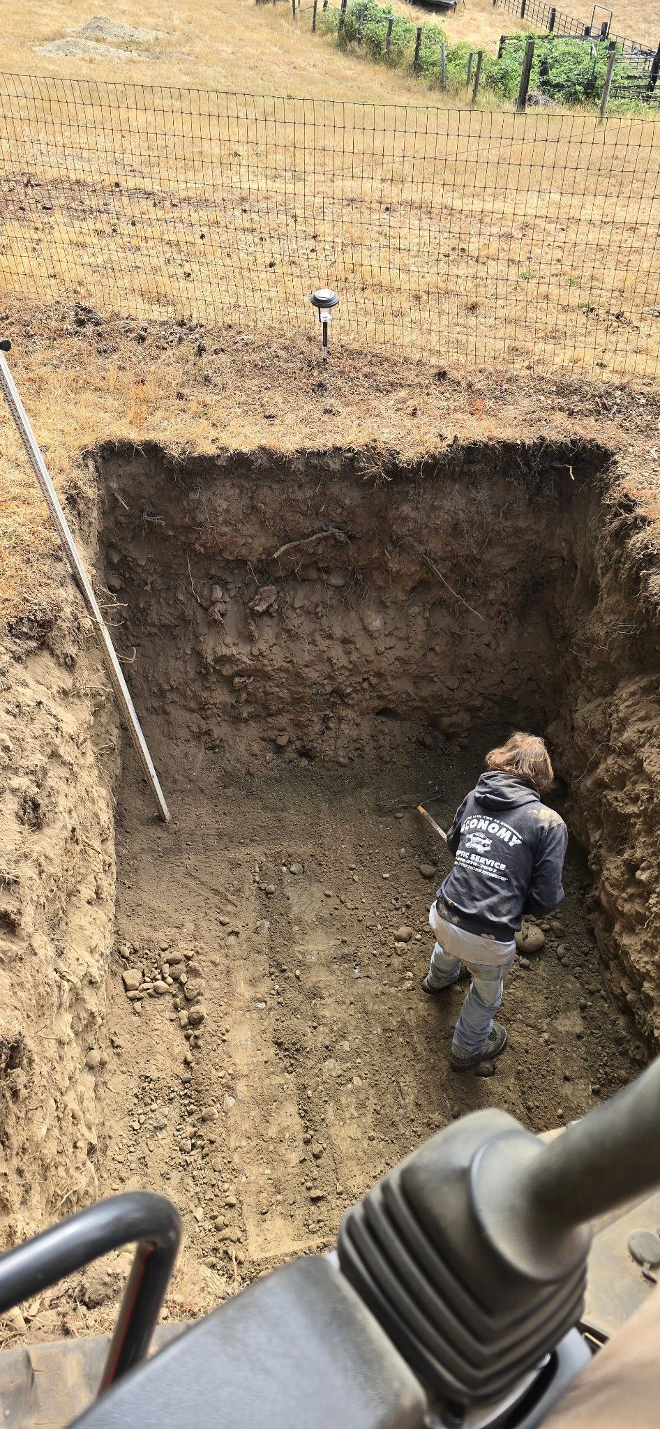 A man is digging a hole in the dirt with a shovel.