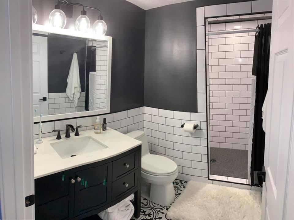 A bathroom with a toilet , sink , mirror and shower.