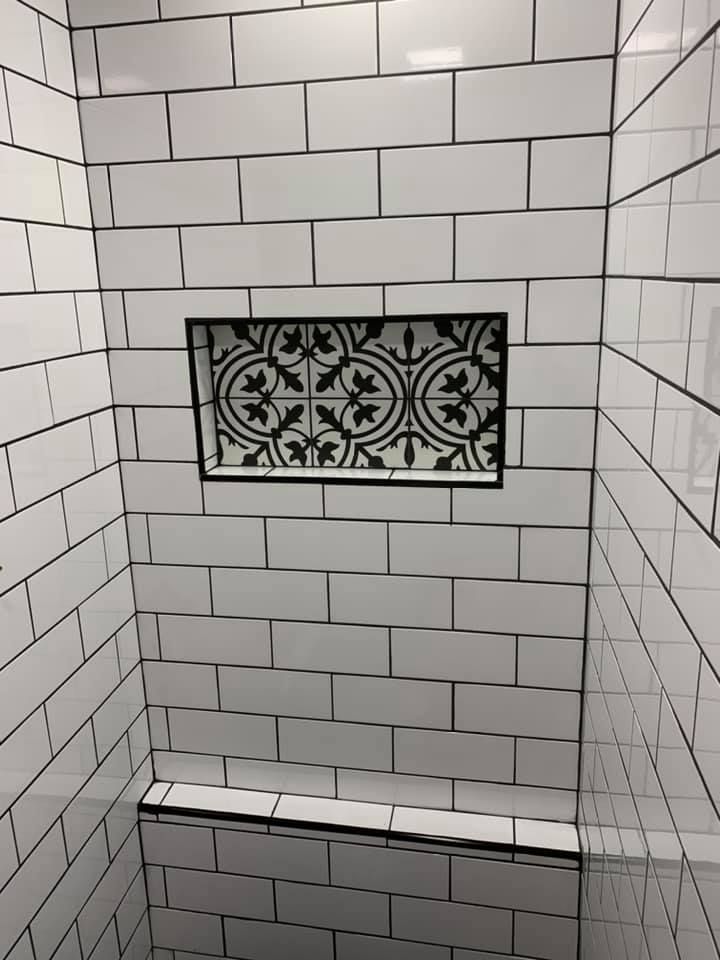 A shower stall with white tiles and a floral design on the wall.
