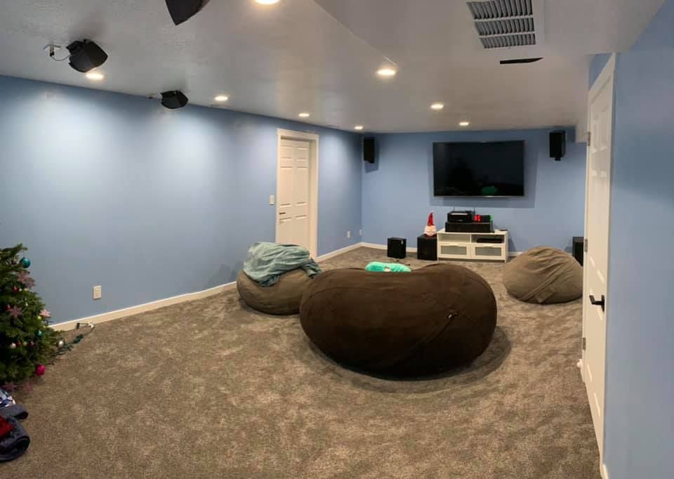 A basement with blue walls , bean bag chairs , a television and a christmas tree.