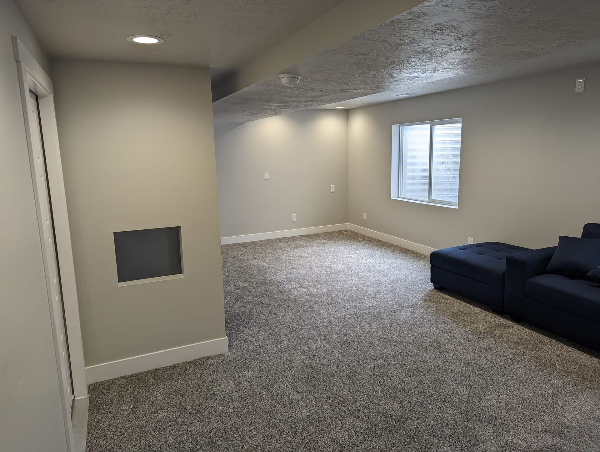 A living room with a blue couch and a window.