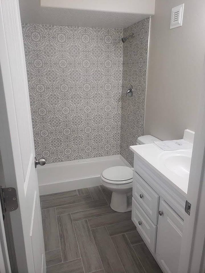 A bathroom with a toilet , sink , bathtub and shower.