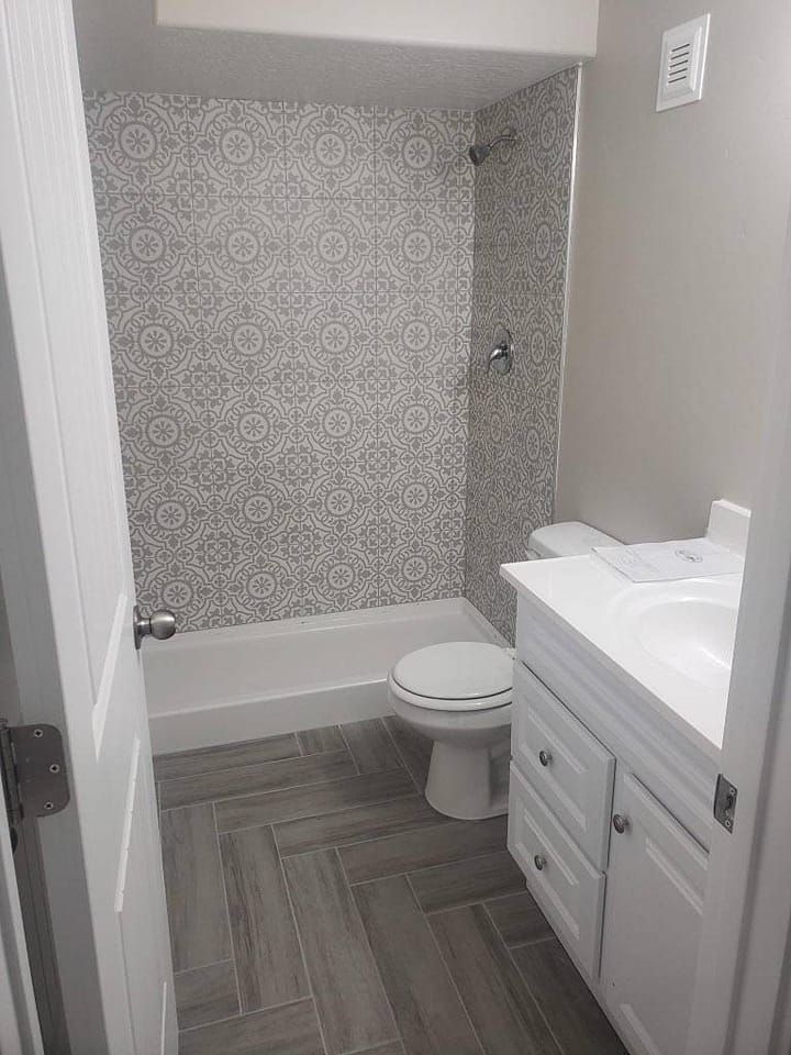 A bathroom with a toilet , sink , bathtub and shower.