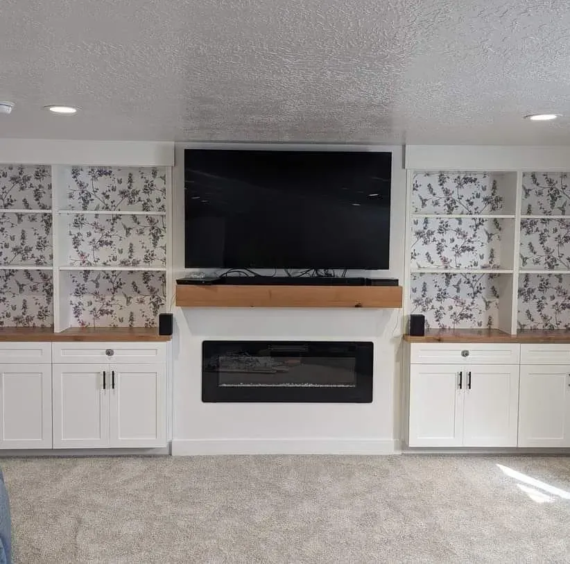 A living room with a fireplace and a flat screen tv on the wall.