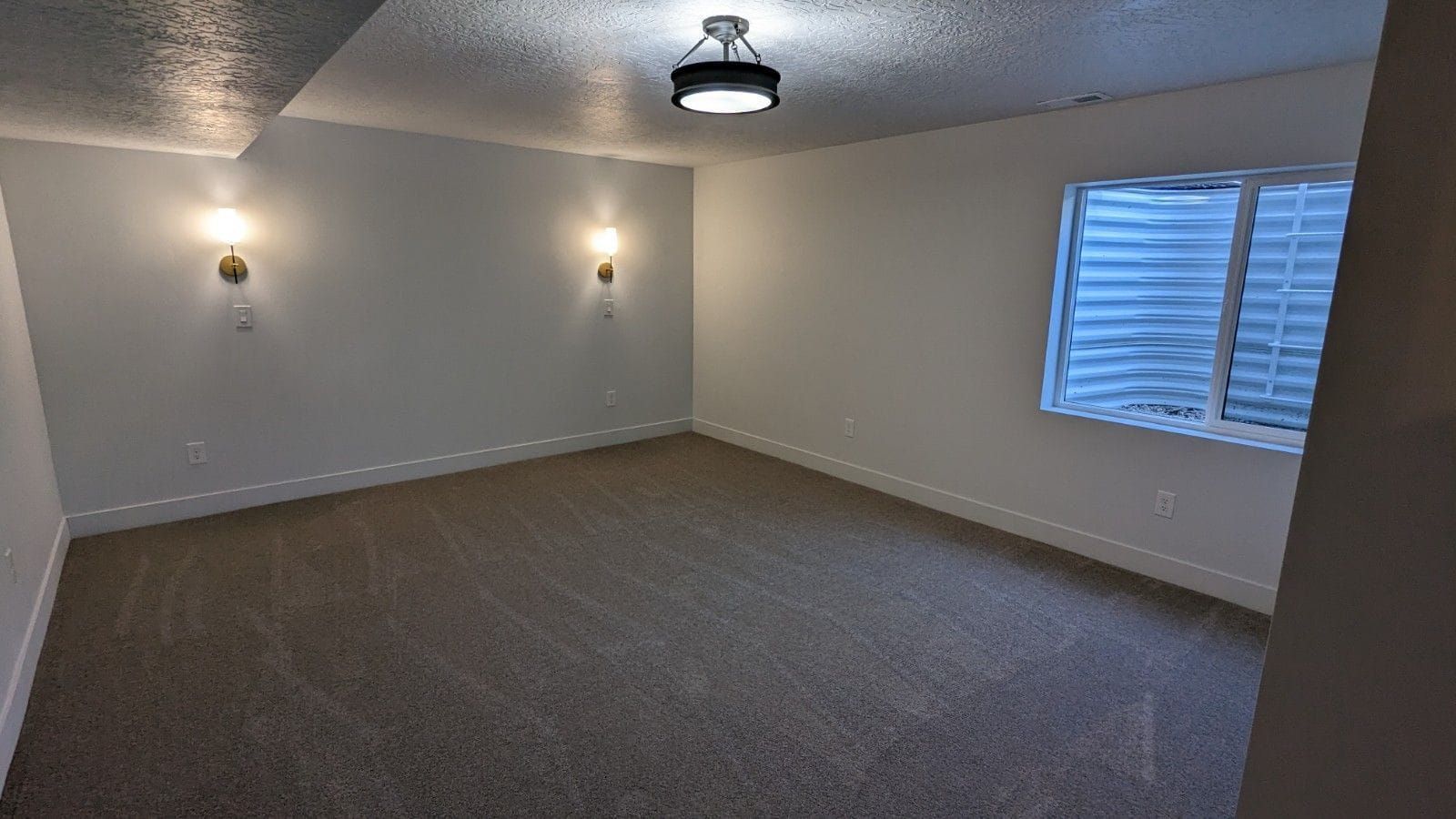 An empty room with a window and a ceiling light.