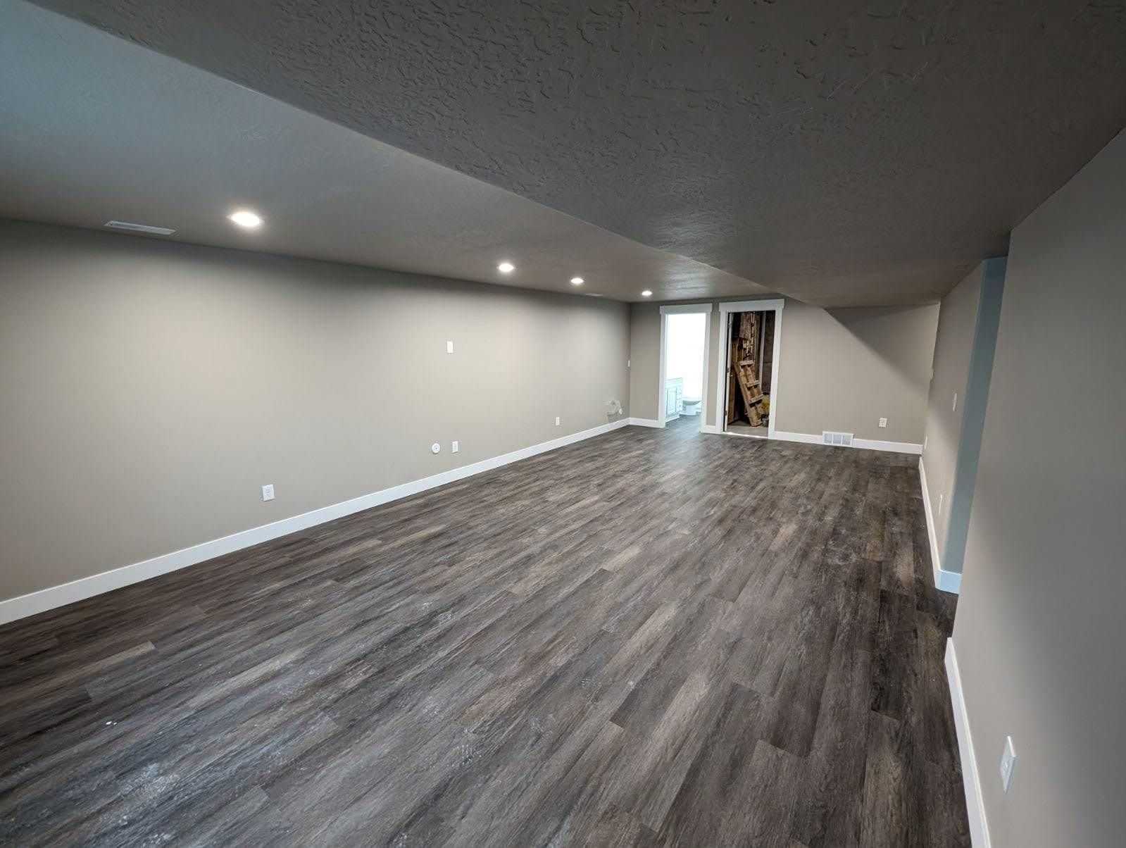 A large empty room with hardwood floors and gray walls.