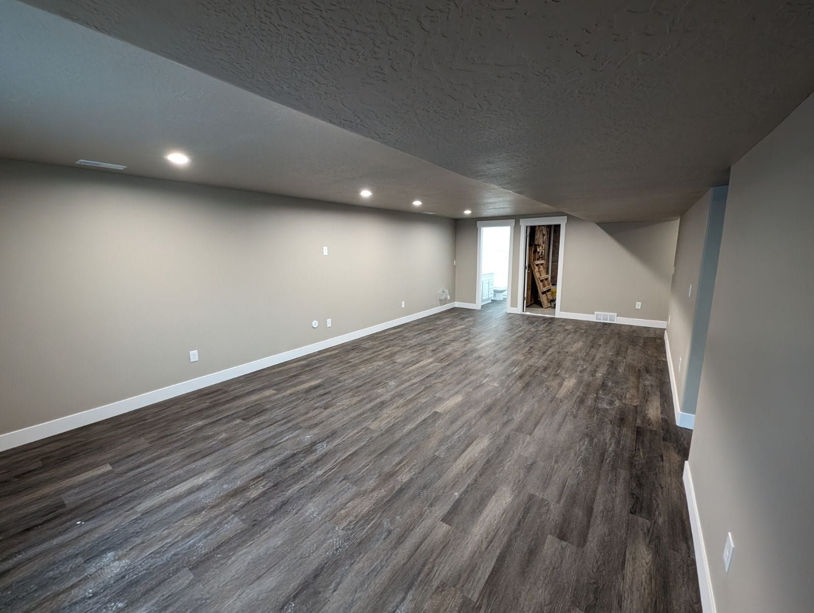A large empty room with hardwood floors and gray walls.
