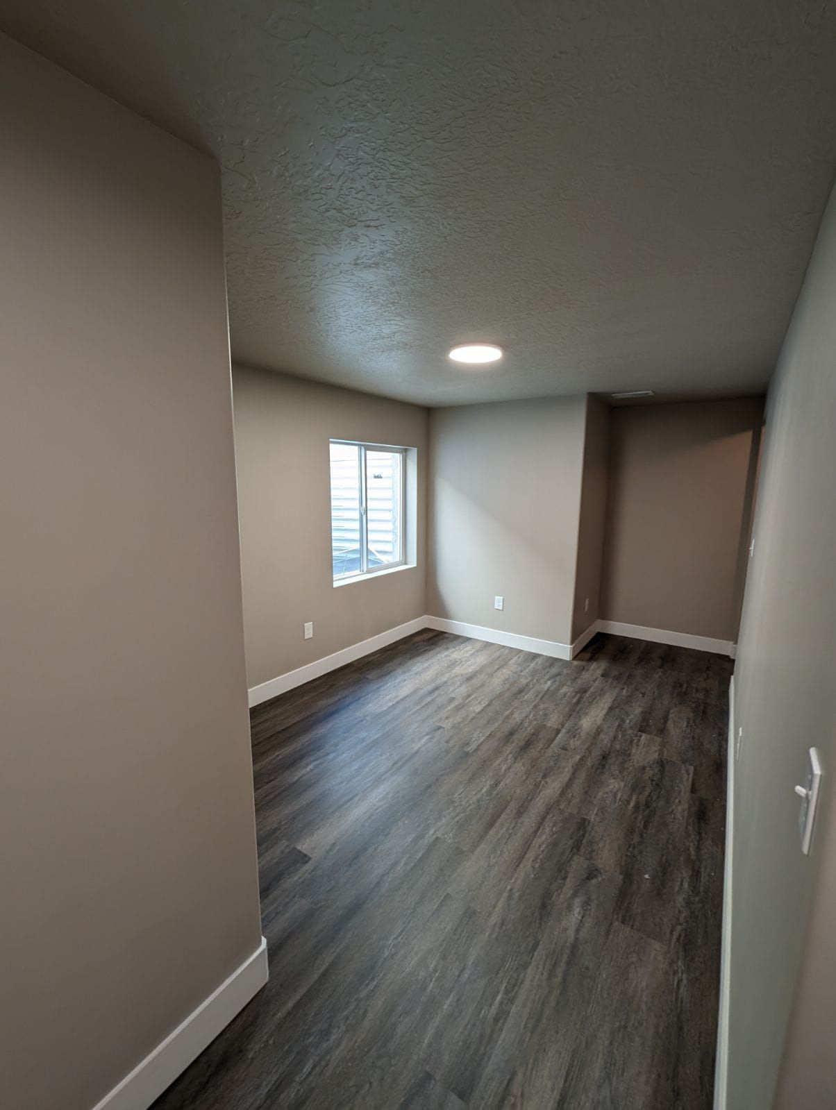 A living room with hardwood floors and two windows.