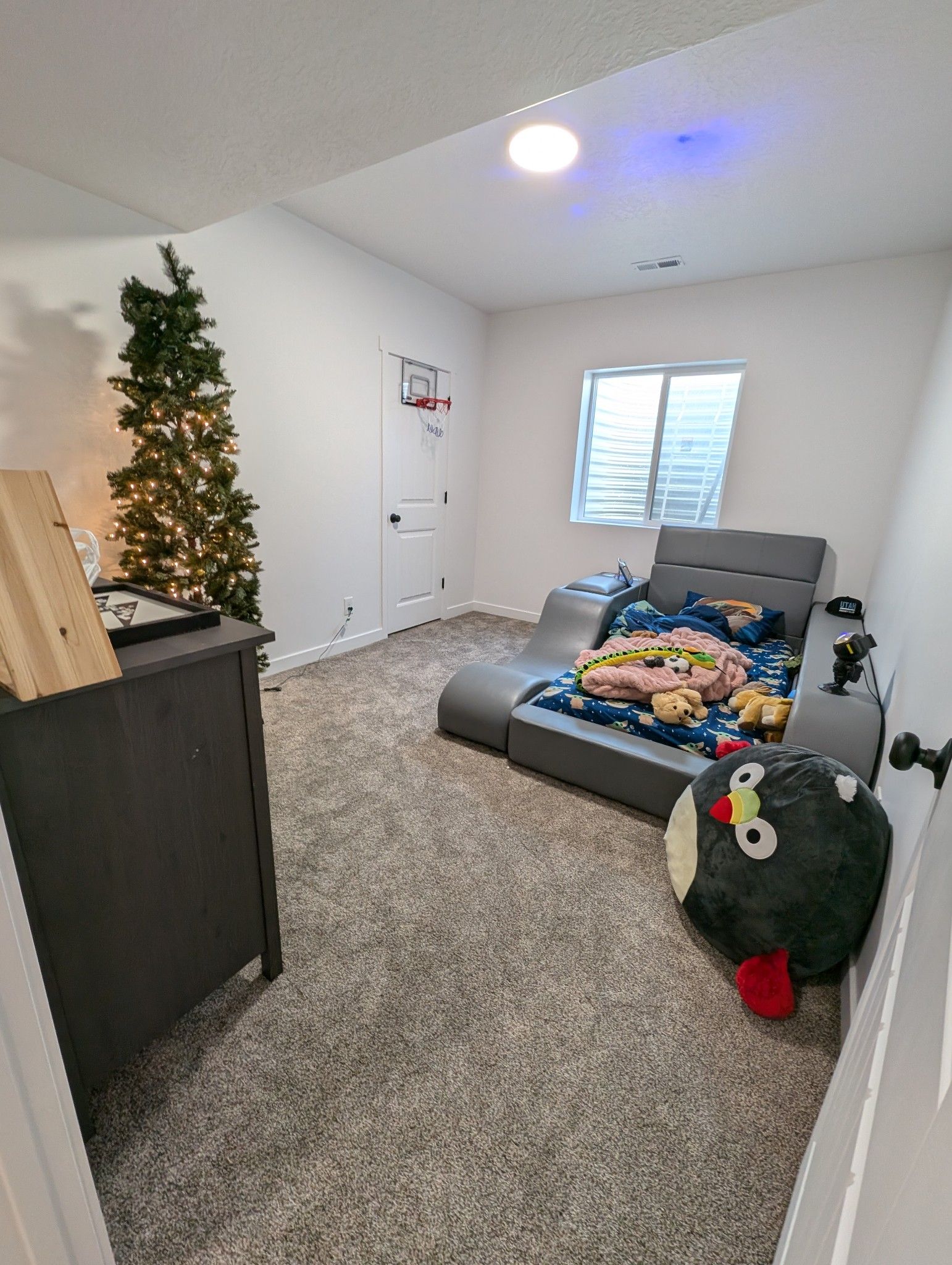 A bedroom with a bed , dresser , and christmas tree.