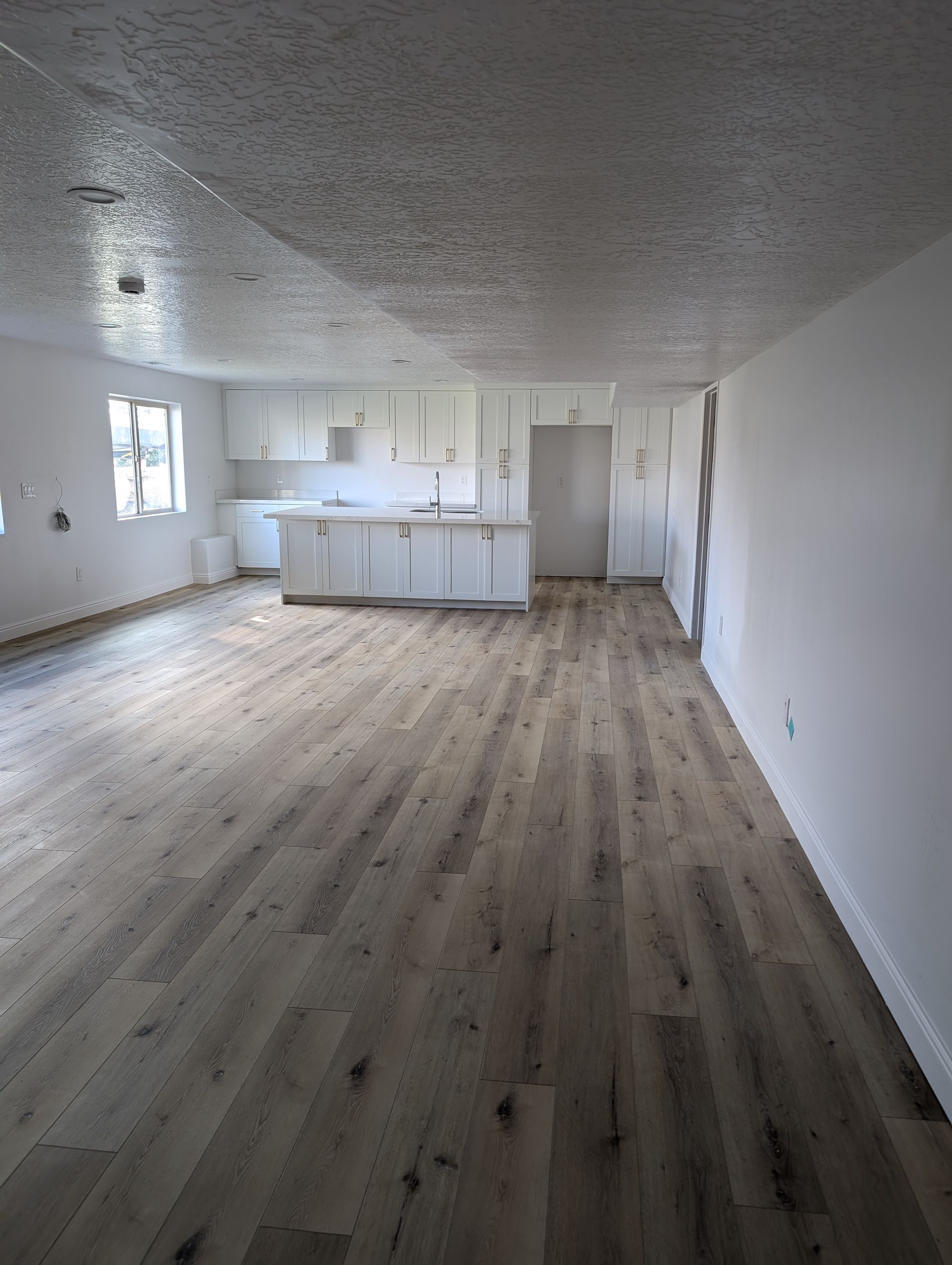 A large empty room with hardwood floors and white walls.