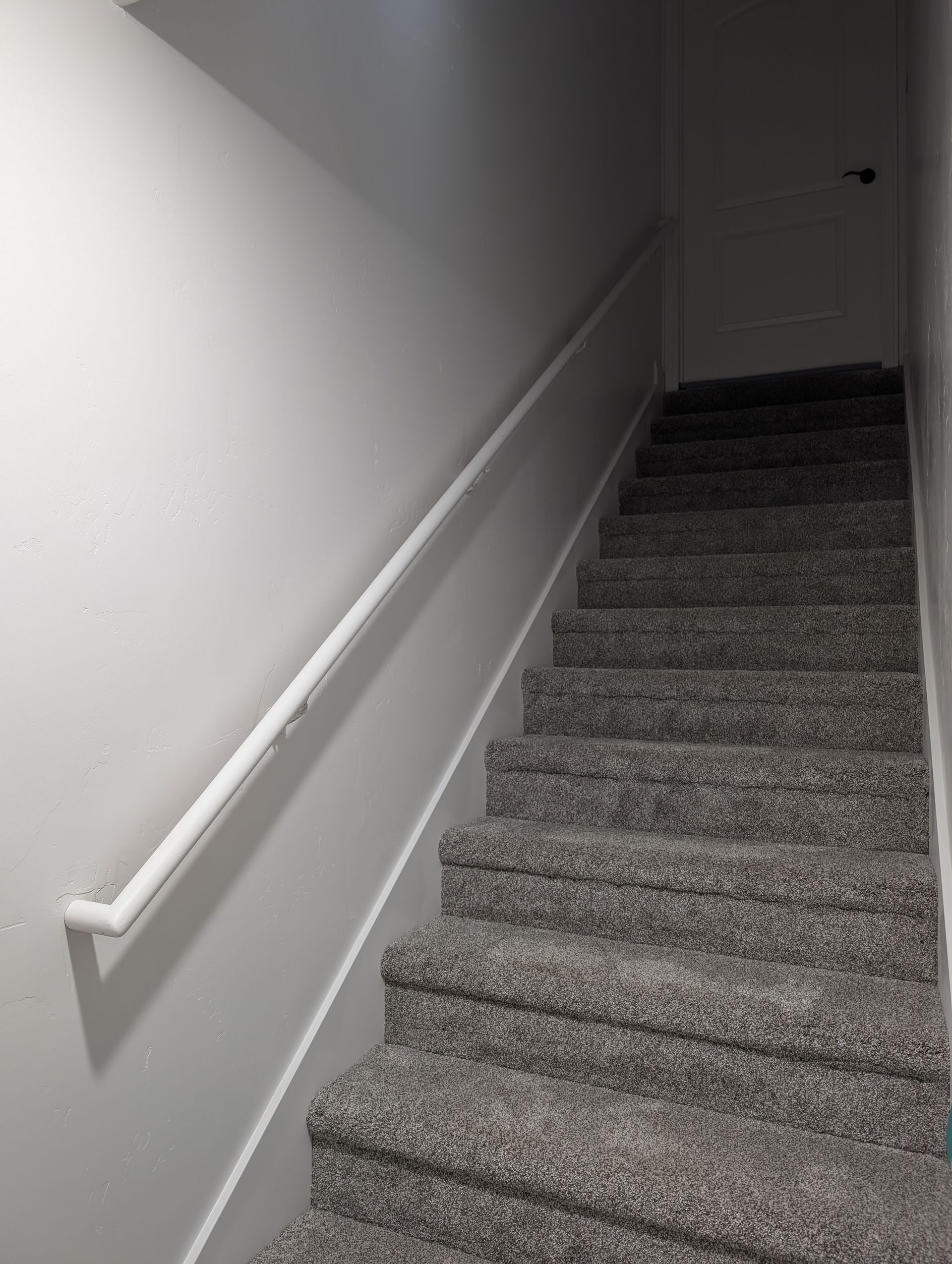 The stairs are carpeted and have a white railing.