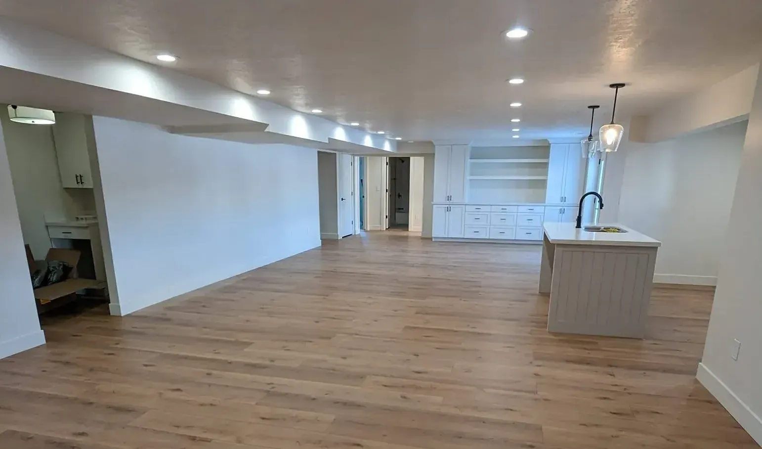 A large empty room with hardwood floors and white walls.