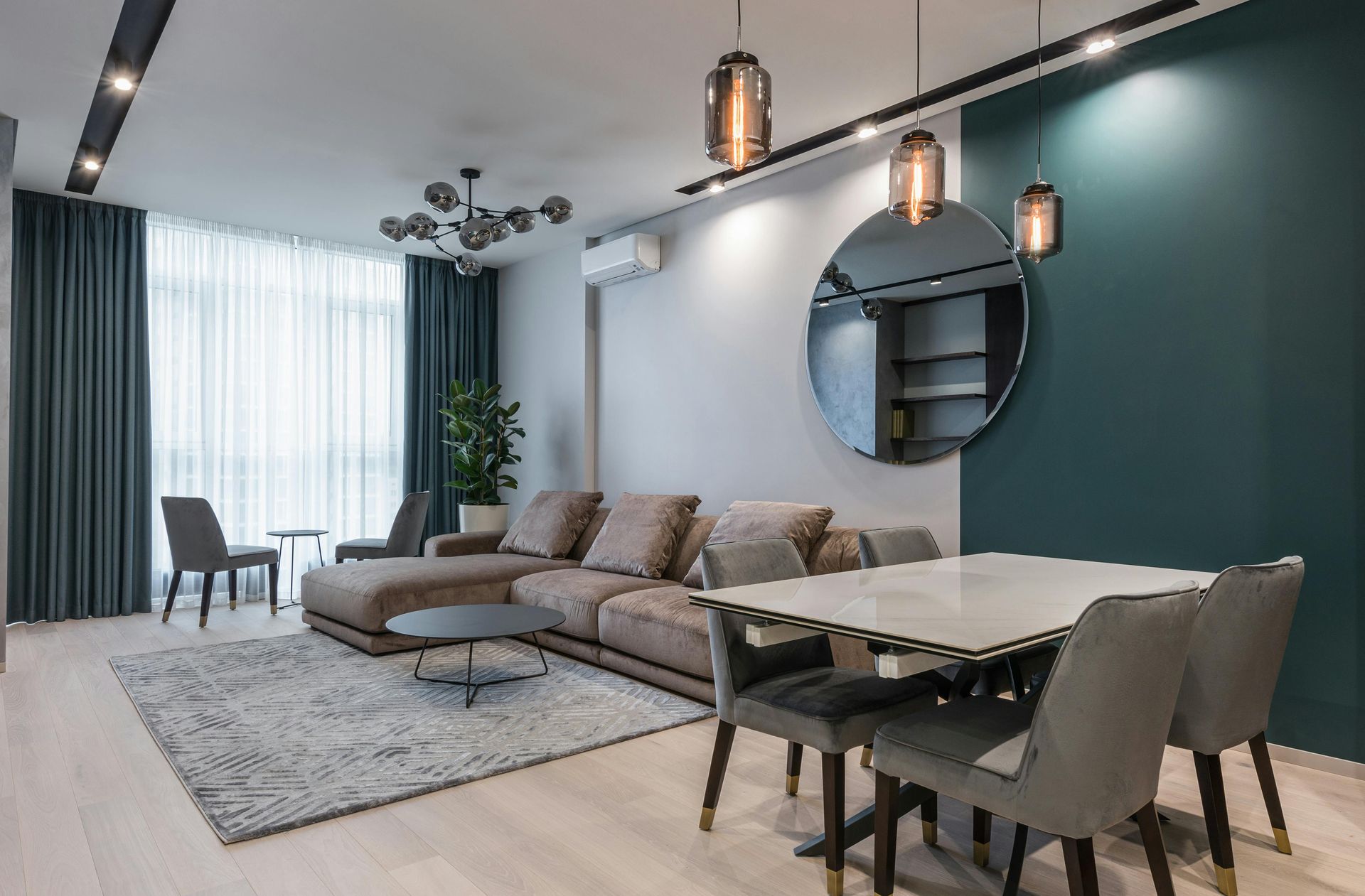 Modern living and dining room with sectional sofa, pendant lights, and green accents.