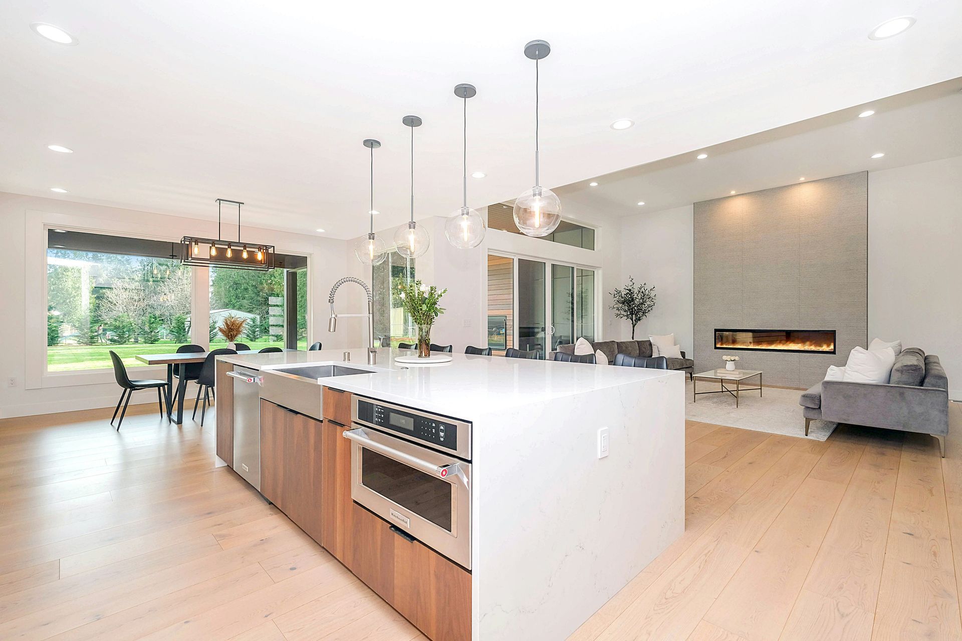 Open-concept kitchen and living room with marble island, pendant lights, and cozy fireplace.