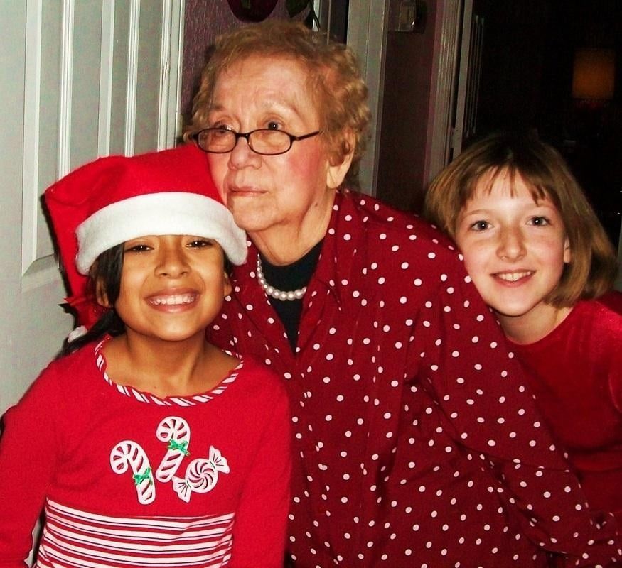 Three people smiling and posing together indoors, dressed in red and white festive holiday clothing.