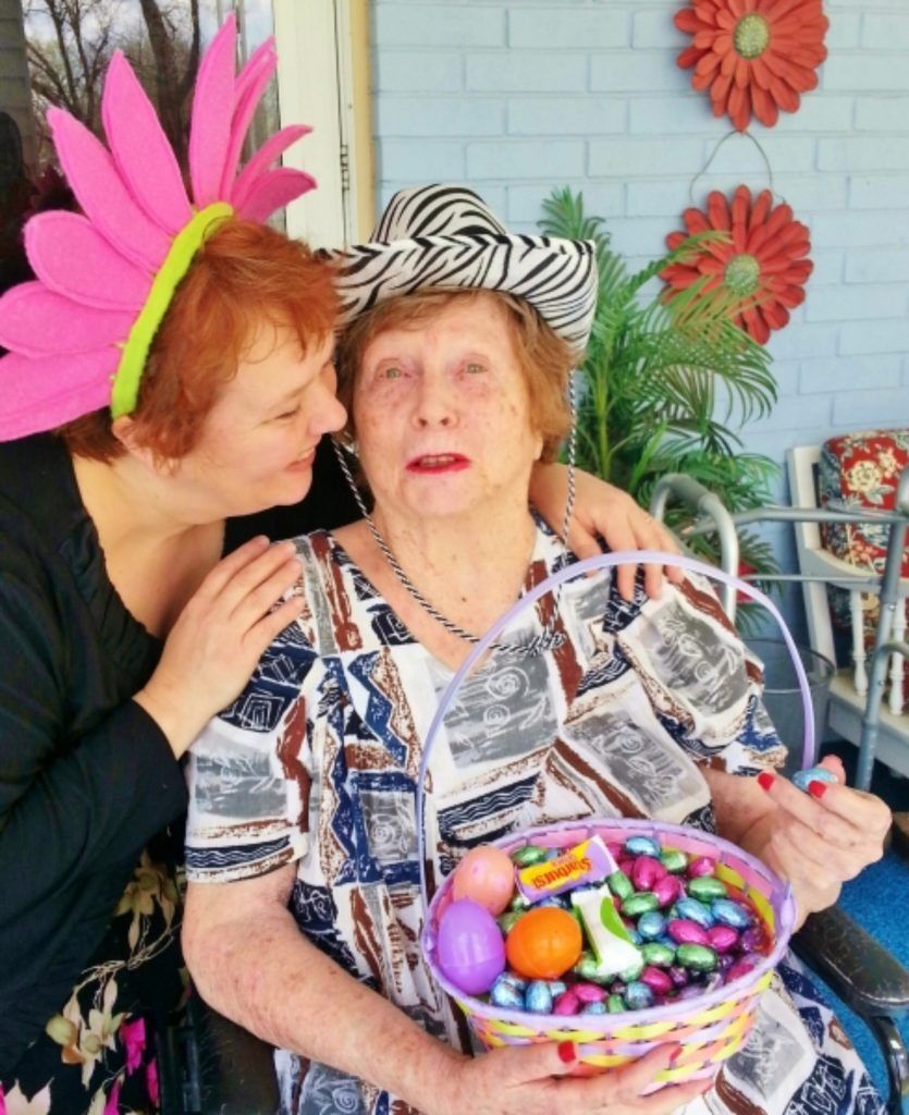 Two people together, one wearing a large pink flower headband, the other in a zebra-print hat holding an Easter basket.