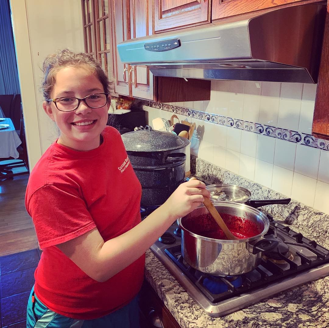 Person smiling while stirring a pot on a stovetop in a kitchen