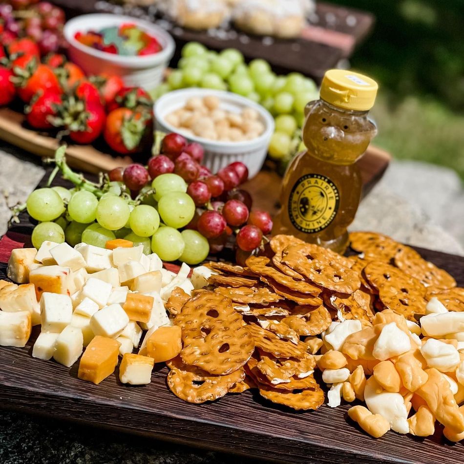Assorted cheese, grapes, crackers, nuts, and honey on a serving tray