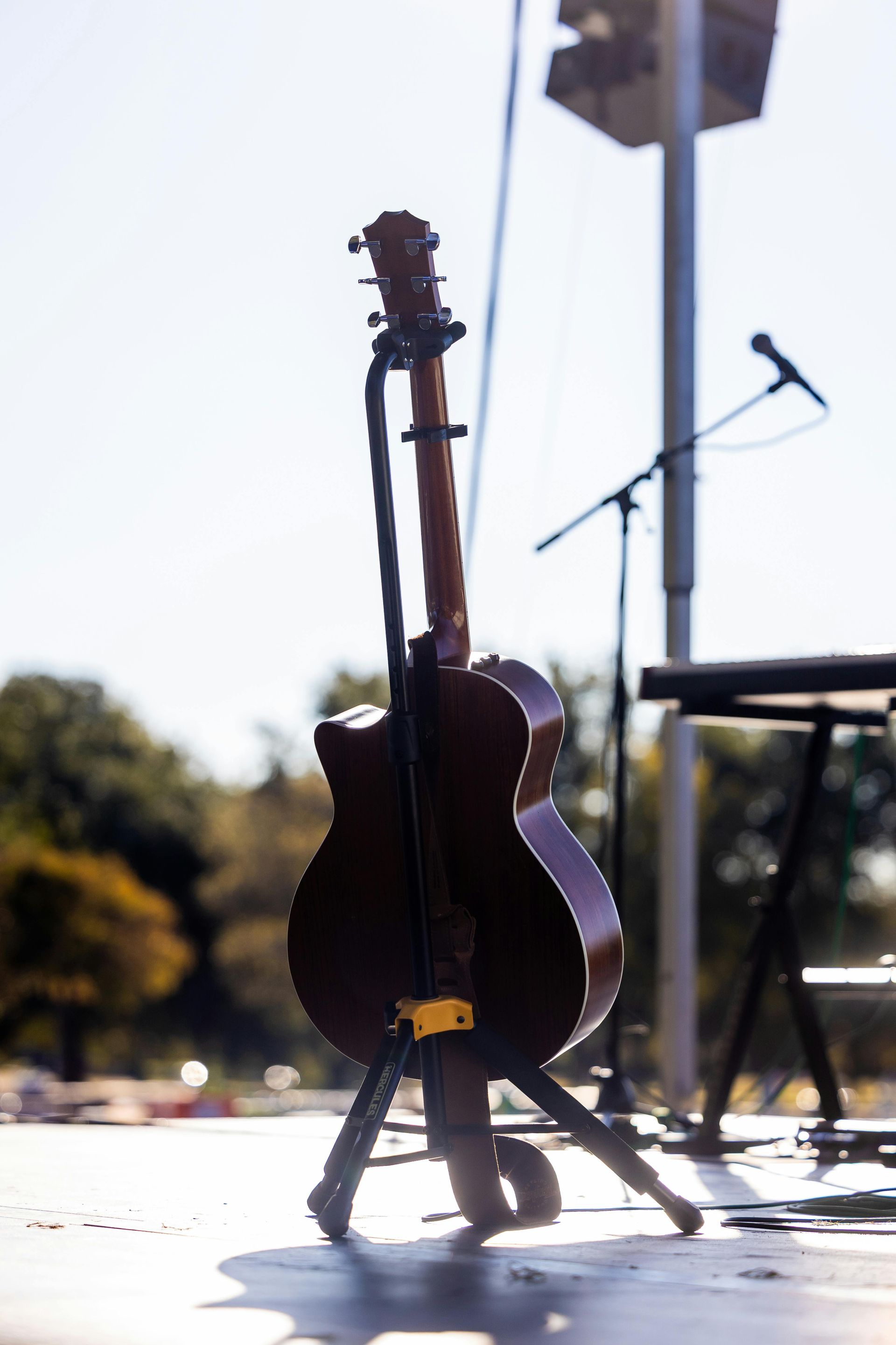 Two string instruments on stands outdoors near a stage microphone
