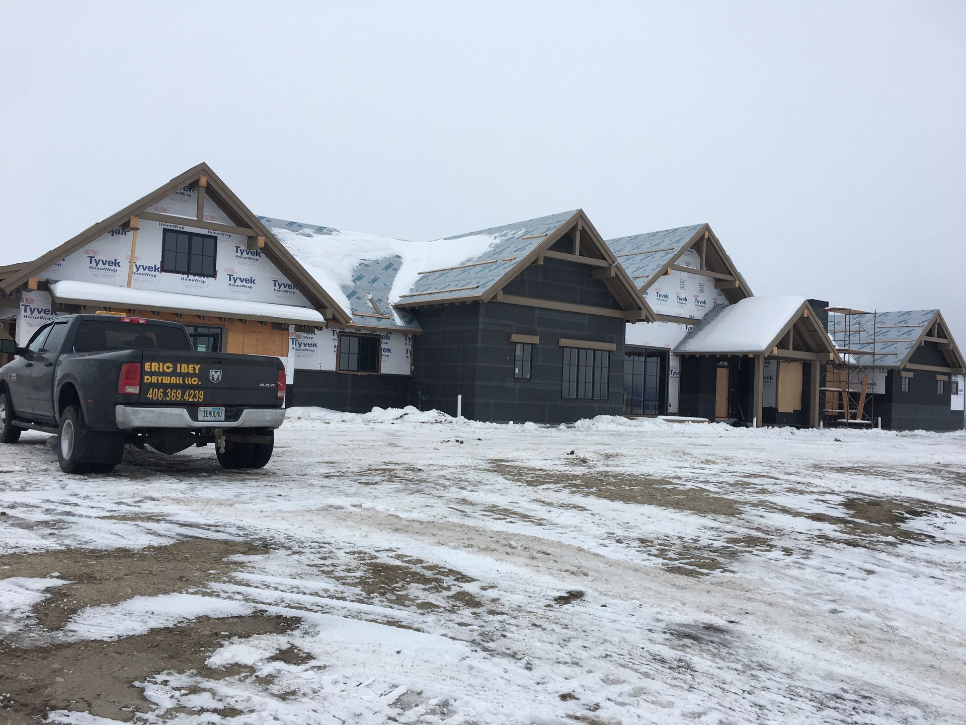 A truck is parked in front of a row of houses under construction.