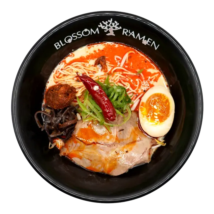 Bowl of ramen with spicy red broth, sliced pork, half-boiled egg, seaweed, and red chili pepper