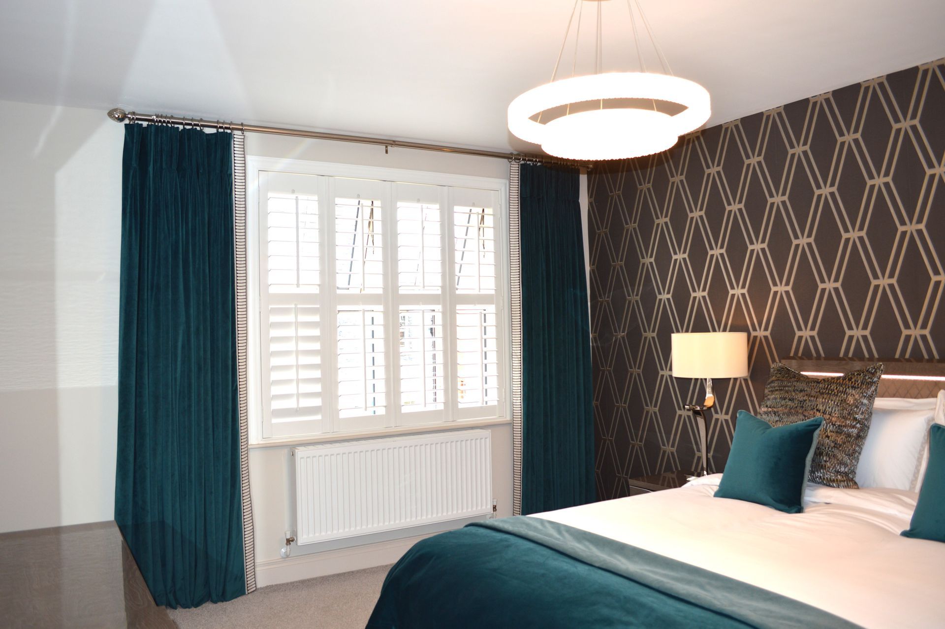A bedroom with a bed , lamps , curtains and a window.