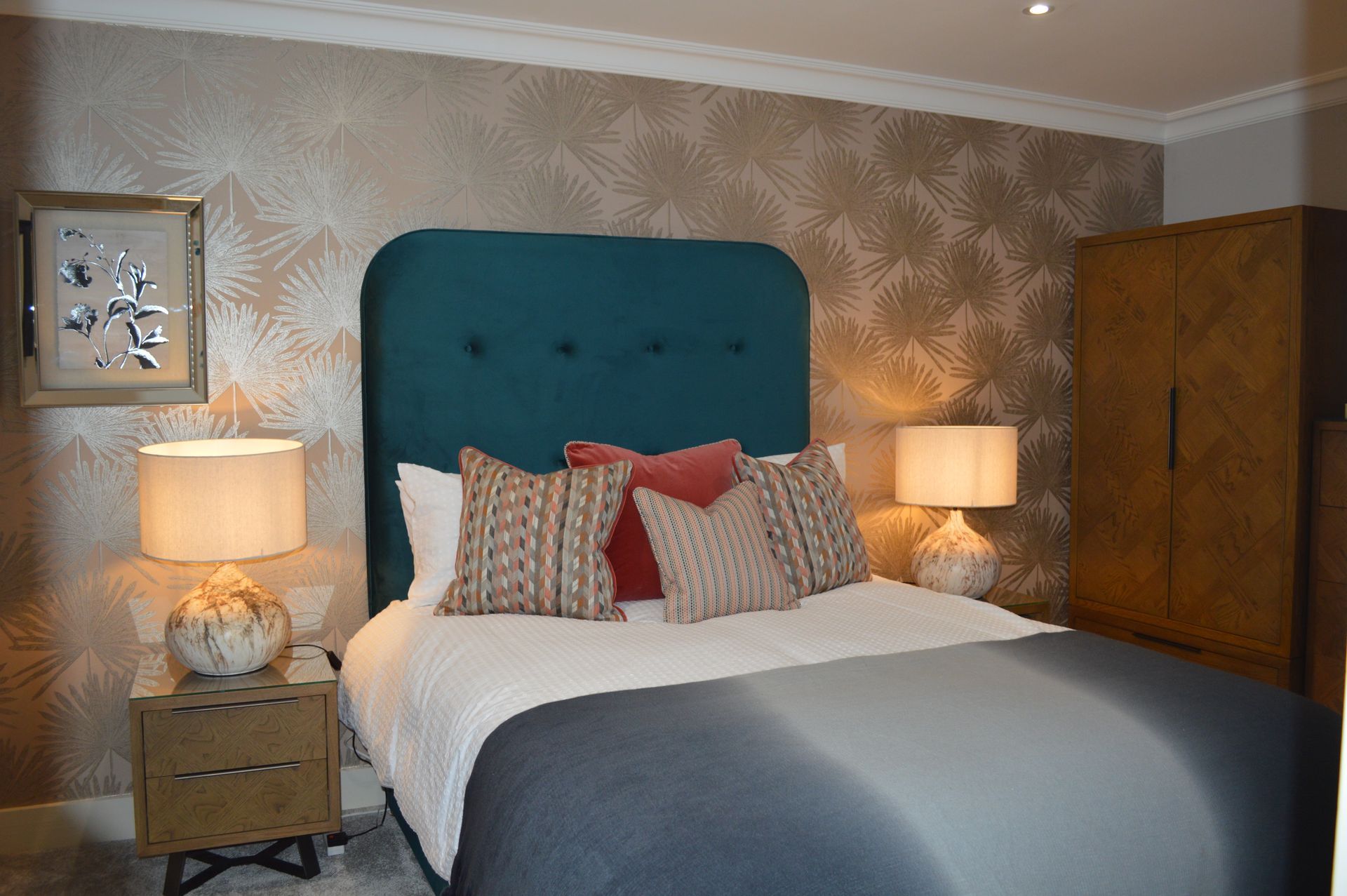 A bedroom with a bed , nightstand , lamps and a picture on the wall.