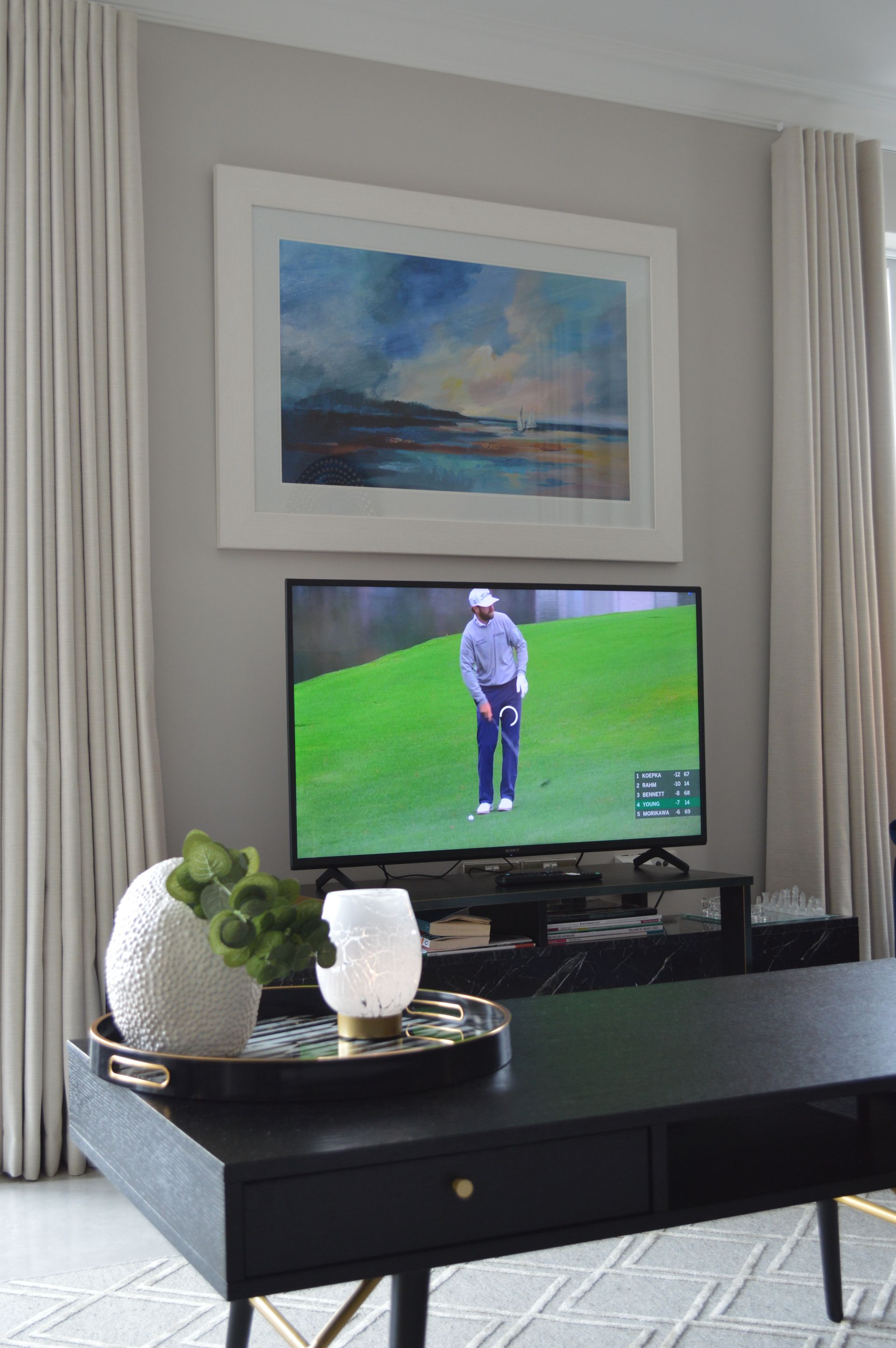 A living room with a flat screen tv and a painting on the wall.