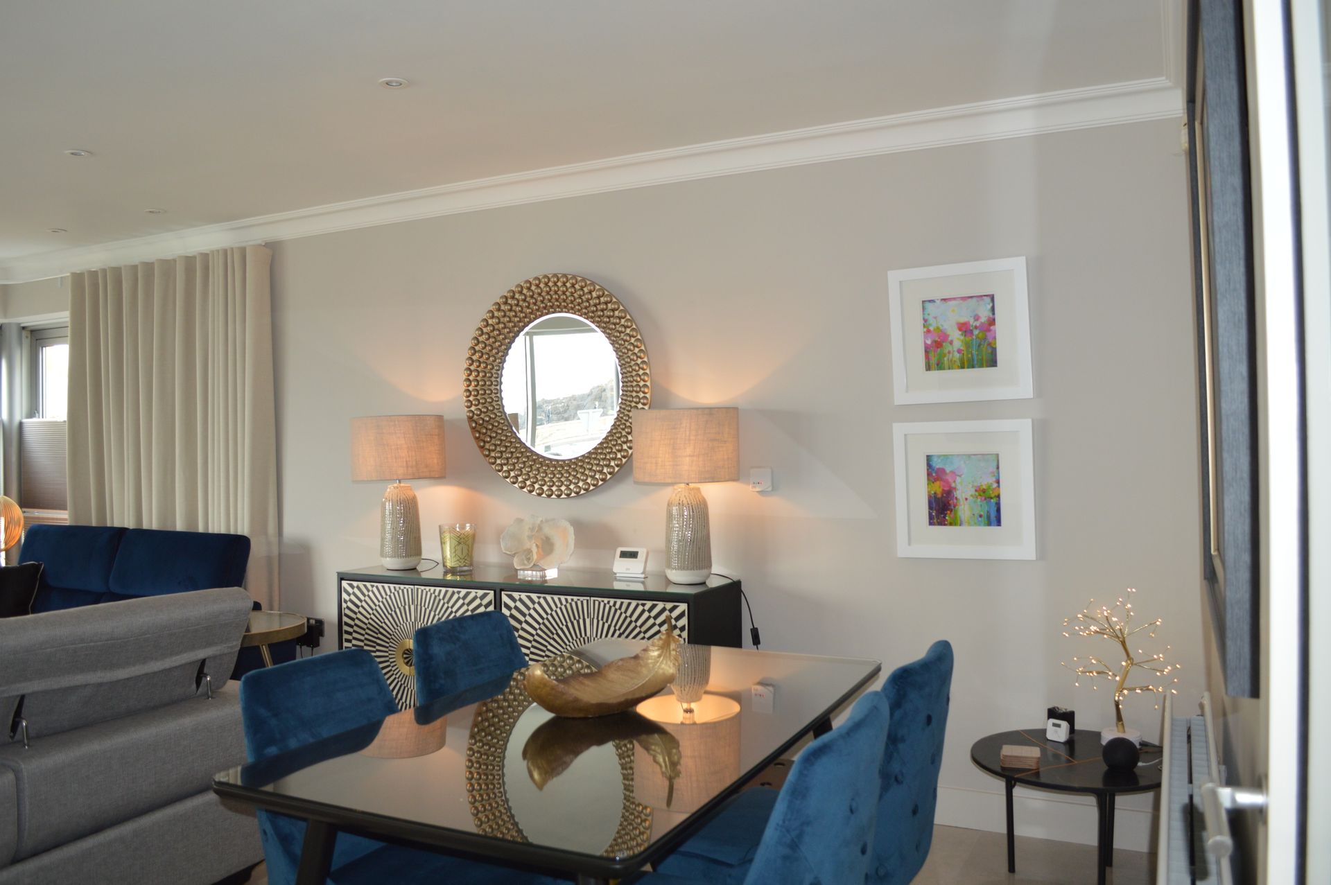 A living room with a dining table and chairs and a mirror.
