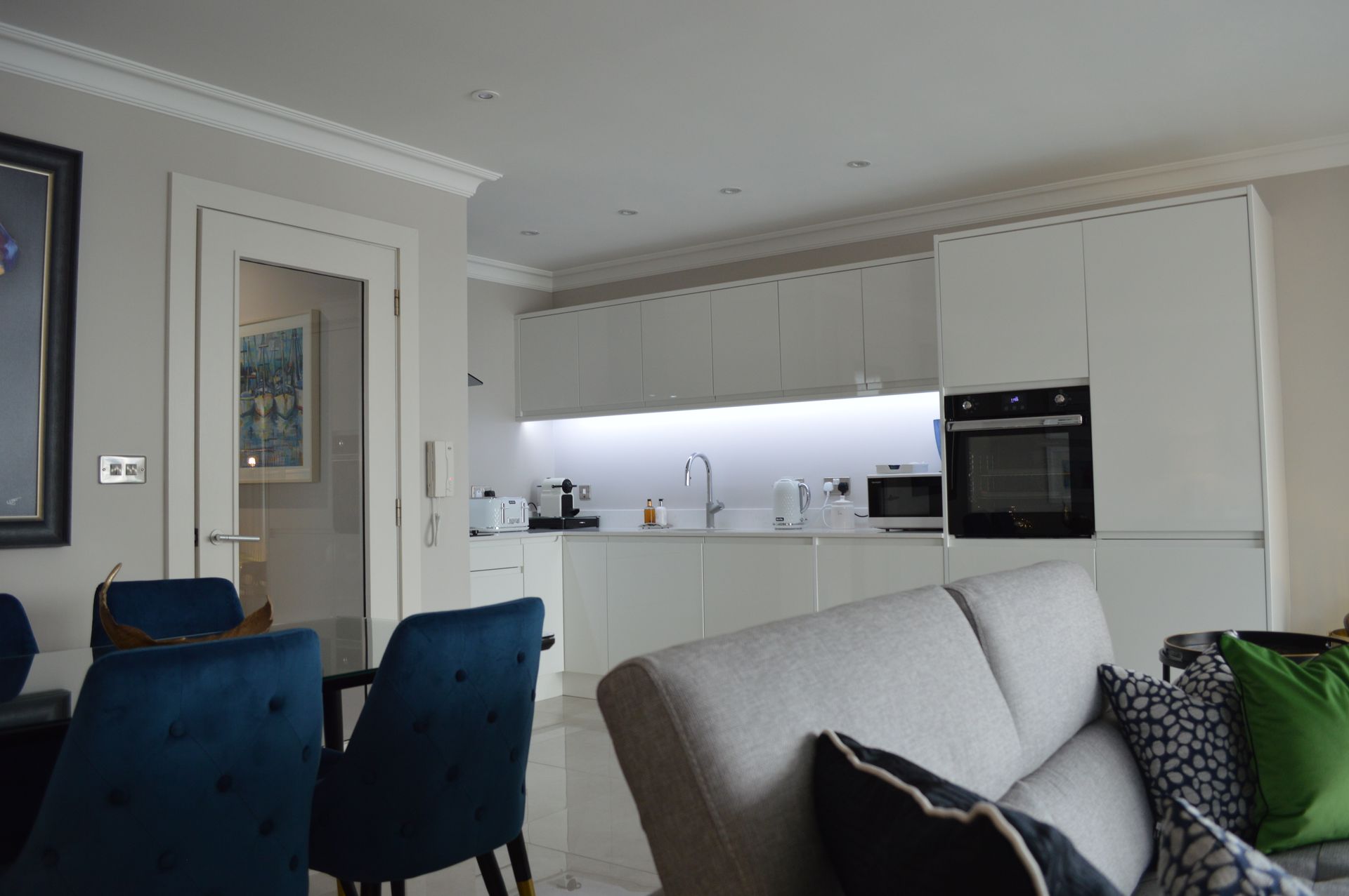 A living room with a couch , chairs , and a kitchen.