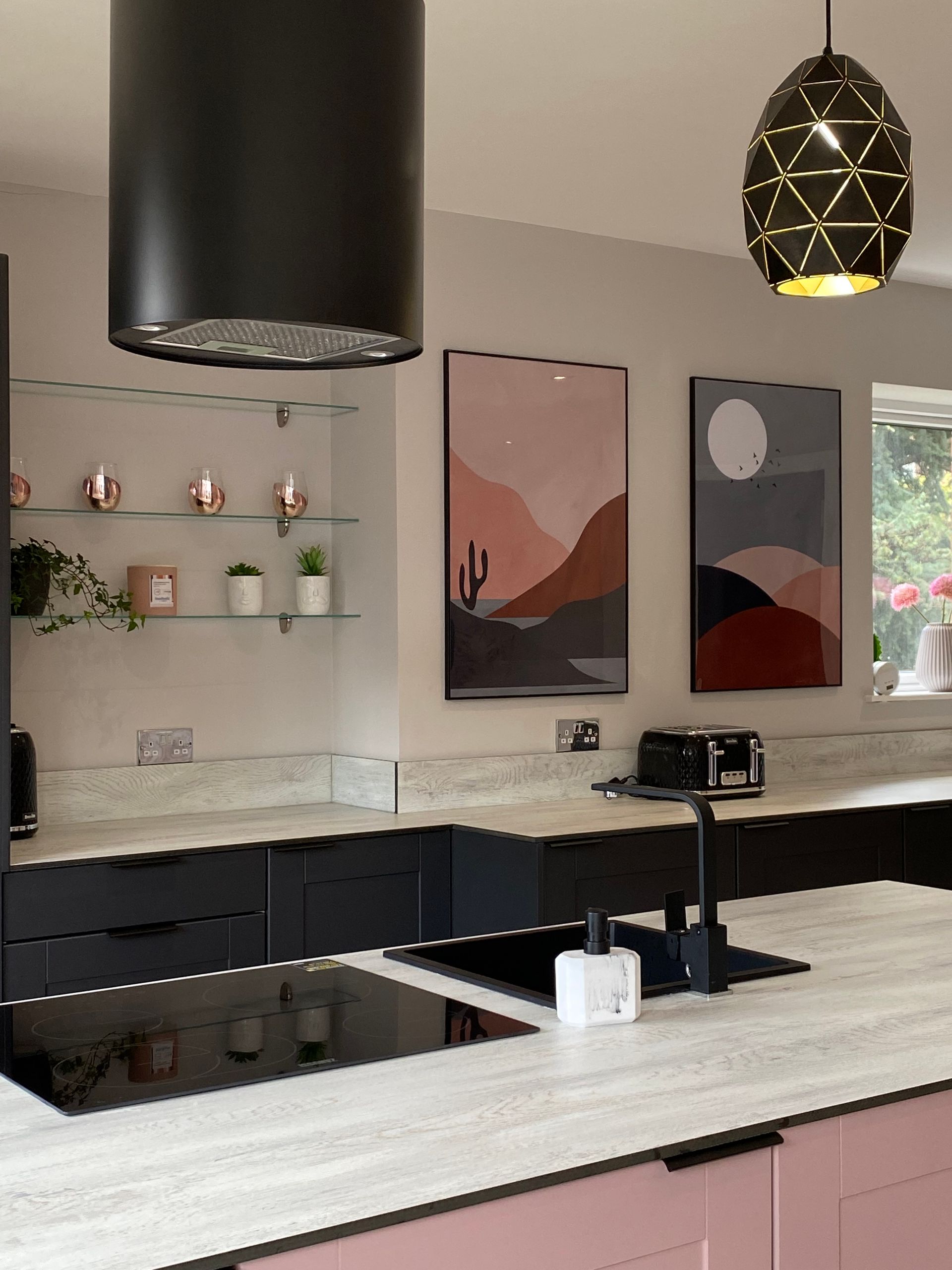 A kitchen with pink cabinets and a black hood