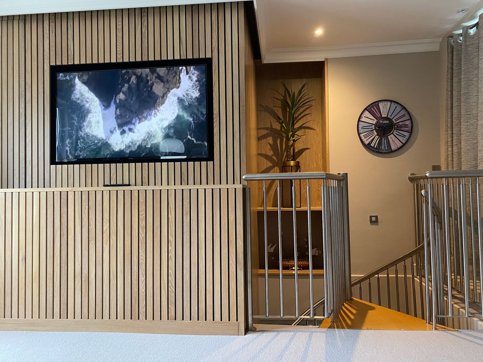 A living room with a clock on the wall and a television on the wall.