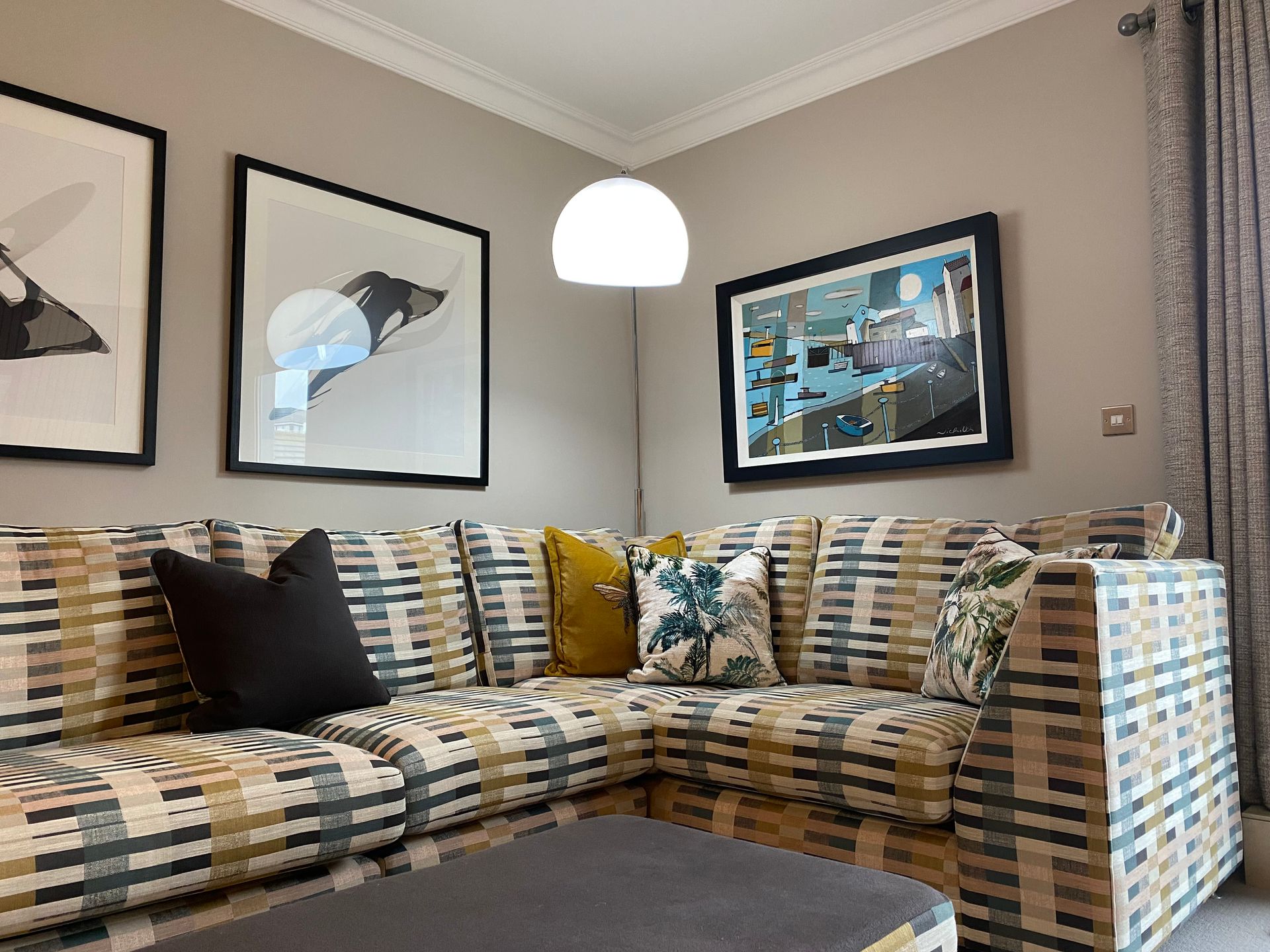 A living room with a couch , coffee table , and paintings on the wall.