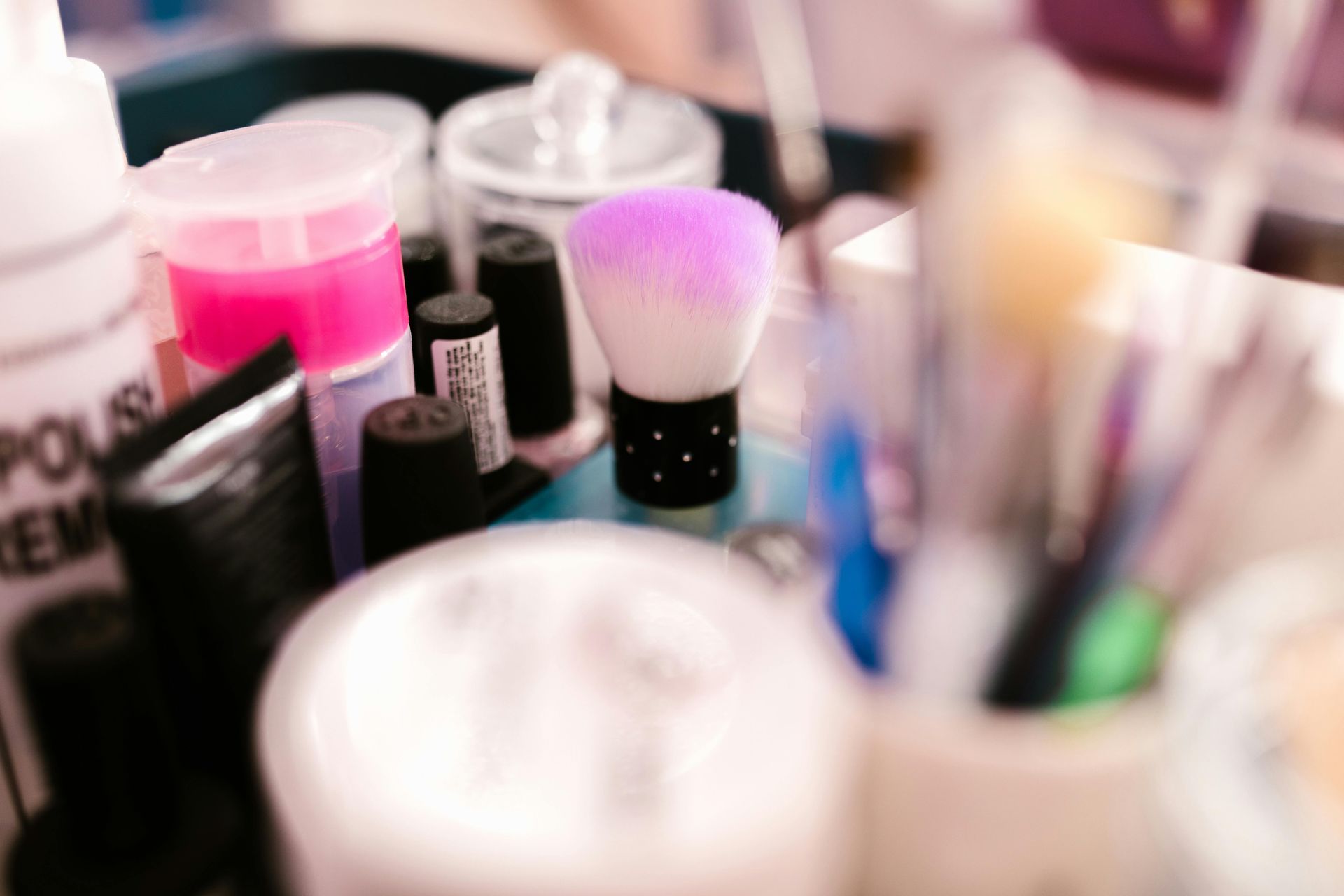 Makeup brush in a jar, surrounded by cosmetic bottles and tools.