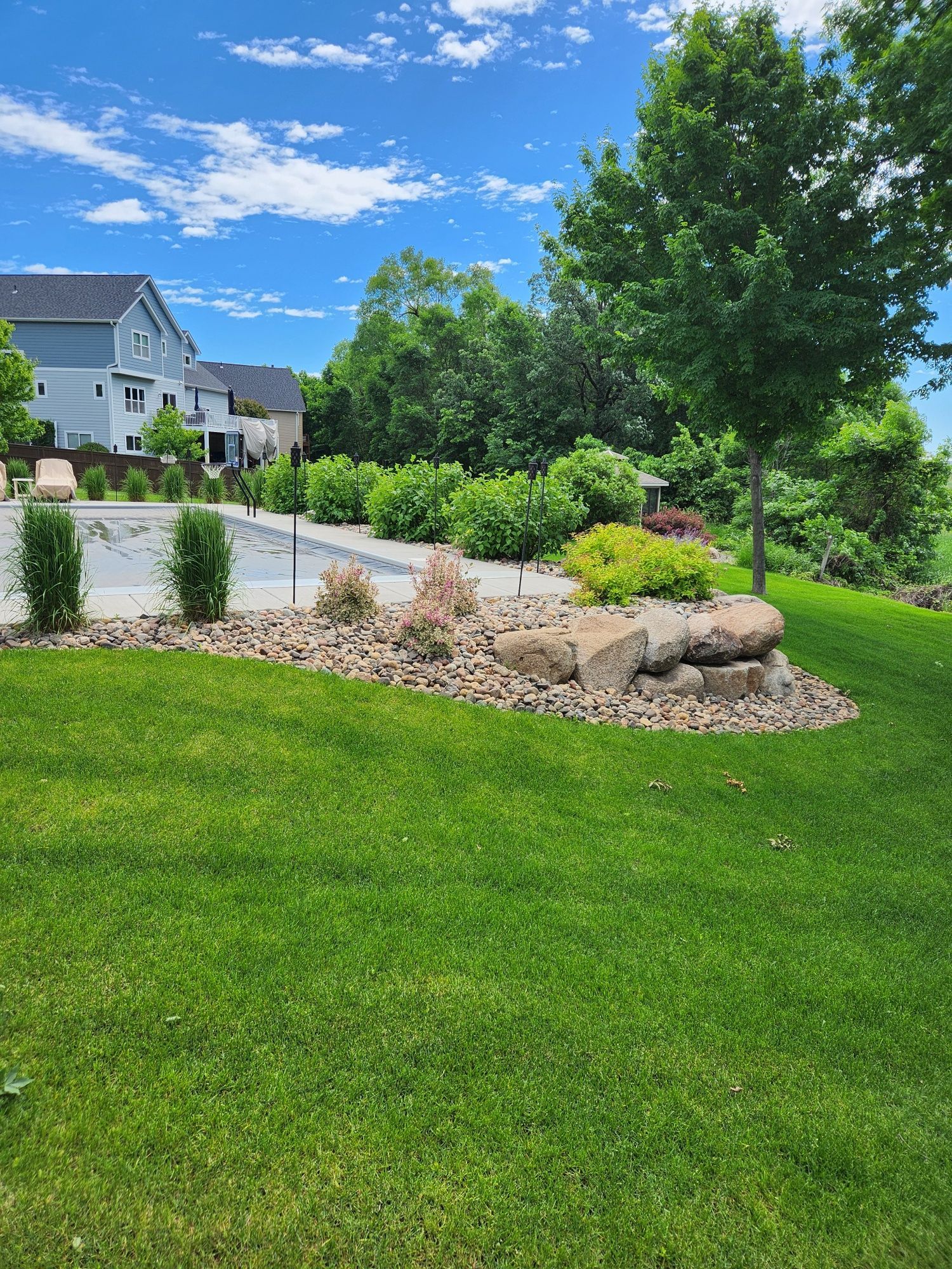 A man is mowing a lush green lawn with a lawn mower.