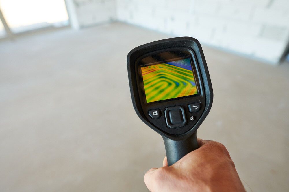 A Person Holds a Thermal Imaging Camera Directed at a Concrete Floor — Leak & Co in Zuccoli, NT 