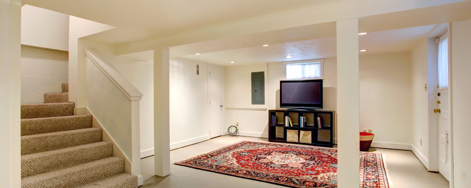 A basement with stairs and a flat screen tv