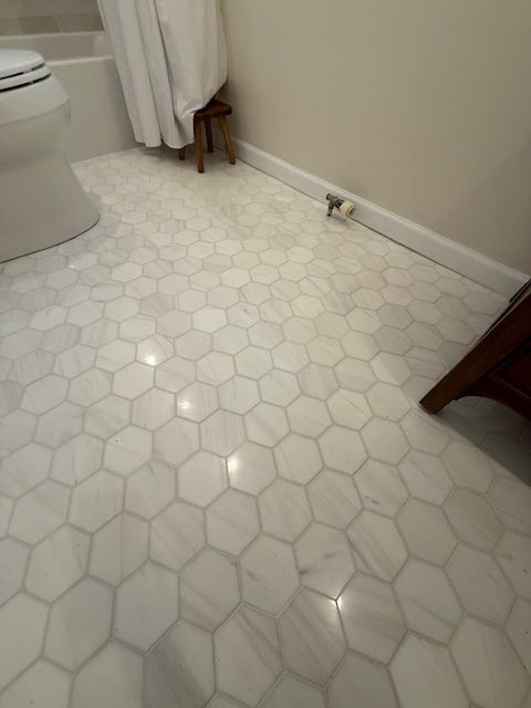 A bathroom with a hexagonal tile floor and a toilet done by Dan Kaplan at Reliable General Contracting