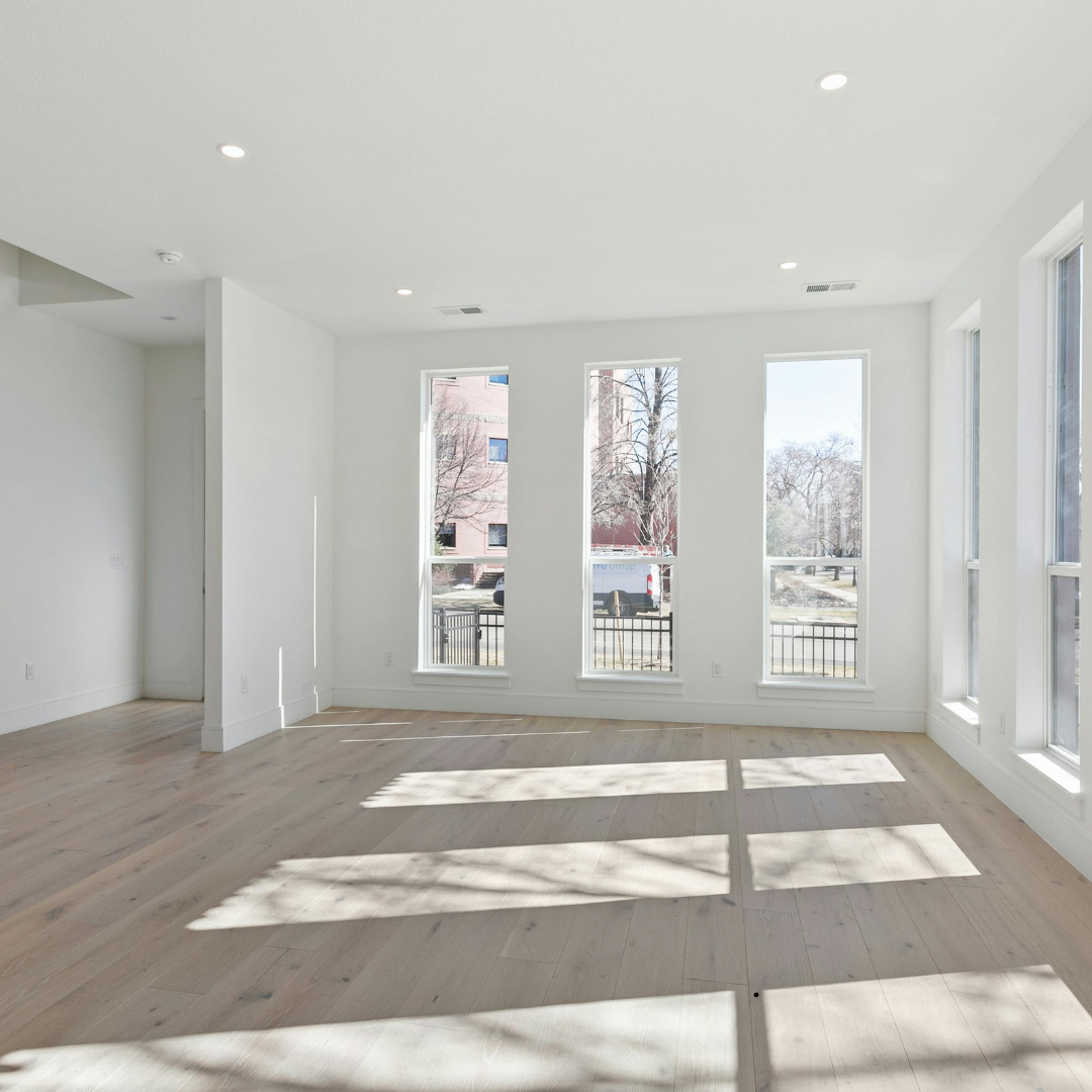 An empty living room with lots of windows and a balcony