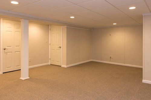 An empty basement with carpeted floors and white walls.