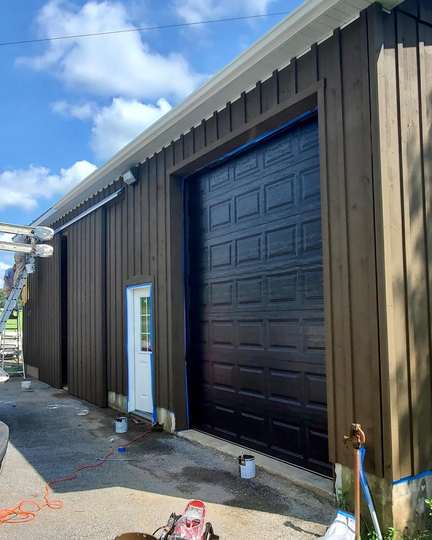 A garage door is being painted black on a building.