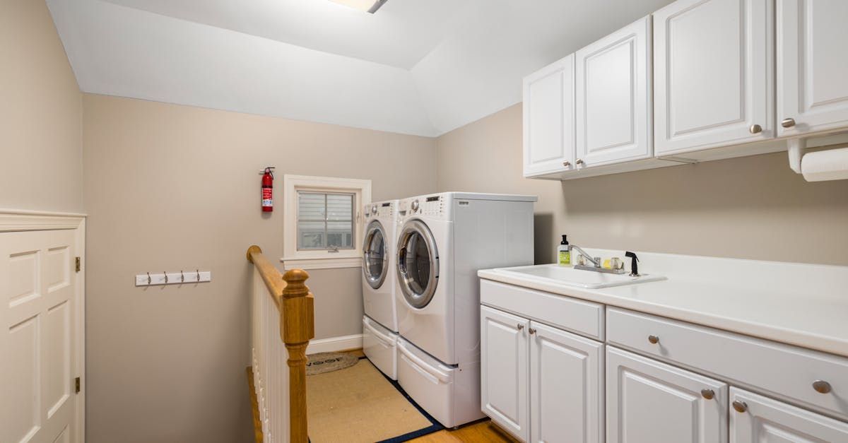 A laundry room with a washer and dryer and white cabinets.